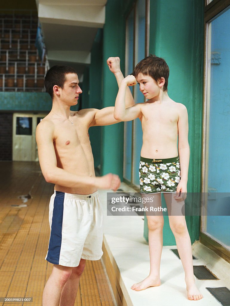 Young man and boy (7-9) comparing flexed biceps