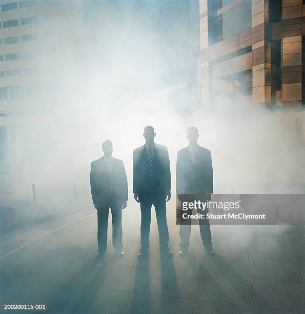 three businessmen standing in a row surrounded by mist - business appearance stock pictures, royalty-free photos & images