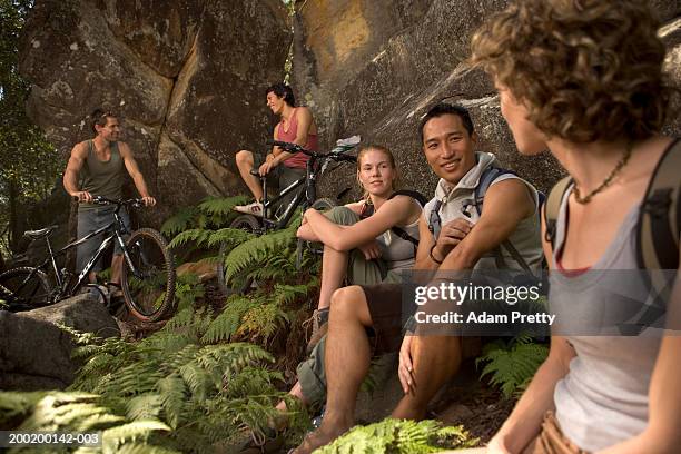 group of young people relaxing by rock face - mountain biking stock pictures, royalty-free photos & images