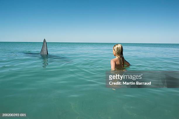 girl (8-10) facing great white shark, fin breaking surface of sea - shark imagens e fotografias de stock