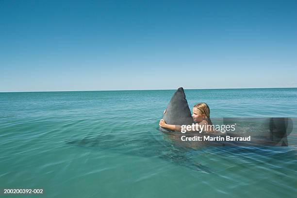 girl (8-10) holding onto fin of great white shark in sea - animal fin - fotografias e filmes do acervo