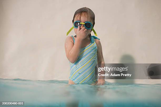 girl (3-5) standing in swimming pool, wearing goggles and holding nose - pinching nose stockfoto's en -beelden