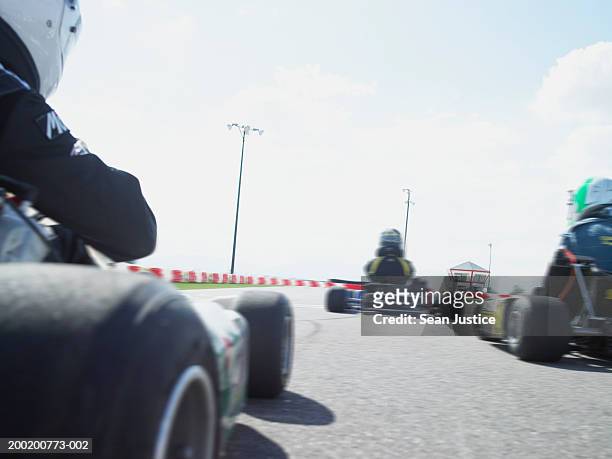 go-cart drivers racing on track, rear view (blurred motion) - corrida de cart - fotografias e filmes do acervo