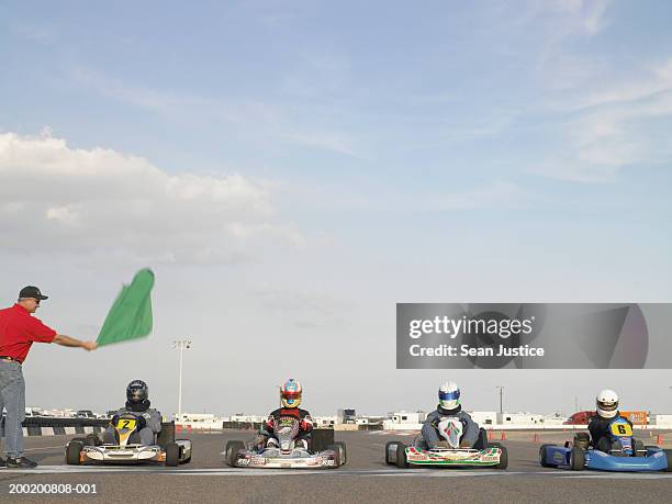 go-cart racers at start line, man waving green flag - go carting stock pictures, royalty-free photos & images