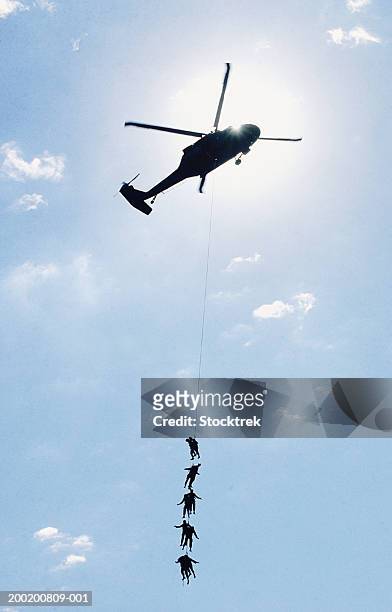 soldiers on rope hanging from sikorsky uh-60 blackhawk, low angle view - sikorsky helicopter stock-fotos und bilder