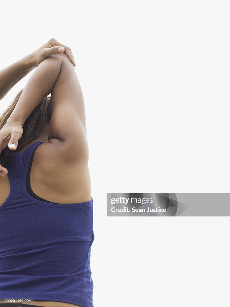 Teenage girl (14-16) stretching arm behind back, rear view