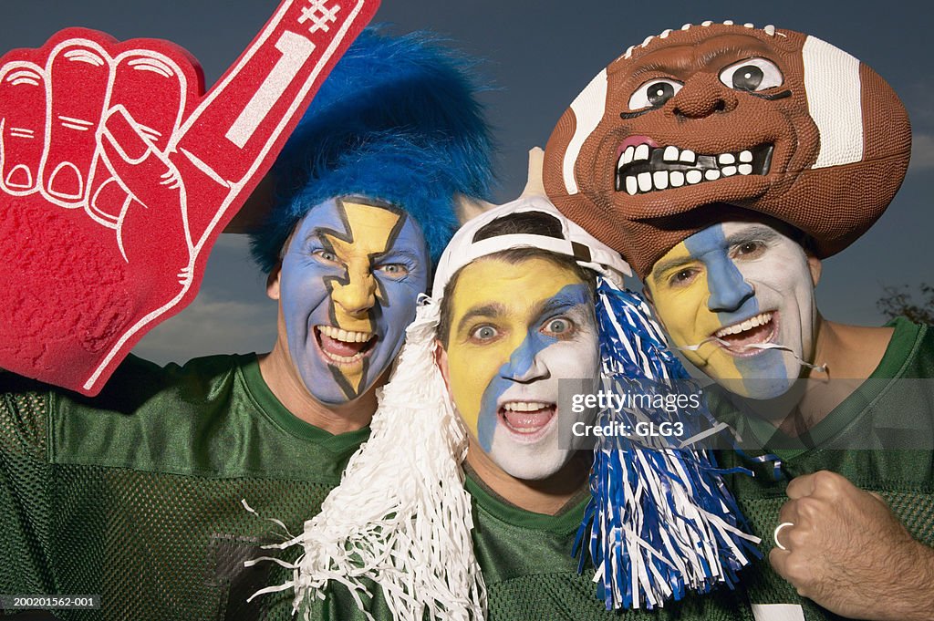 Three male football fans wearing face paint, gesturing