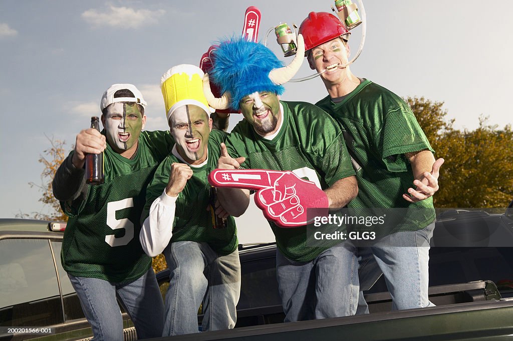 Four male football fans wearing face paint, gesticulating