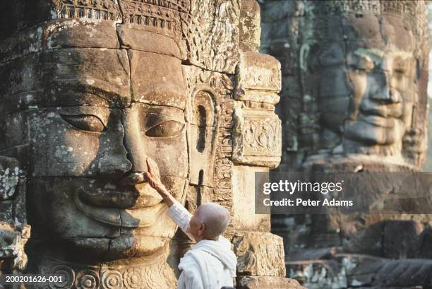 senior buddhist nun touching stone sculptures, rear view - cambodia stock pictures, royalty-free photos & images