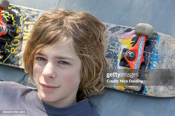 teenage boy (14-16) resting head on skateboard, portrait, close-up - 14 foto e immagini stock