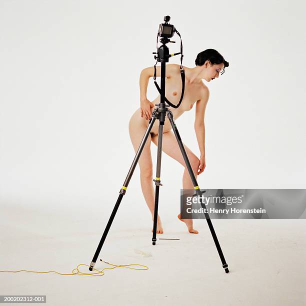 naked woman behind camera tripod, leaning down and to side, profile - pubic hair young women stock-fotos und bilder