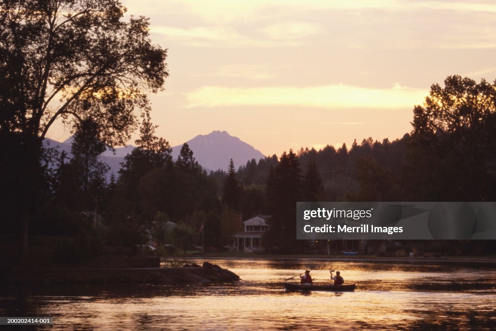 USA, Oregon, Bend, people in canoe on Mirror Pond, sunset