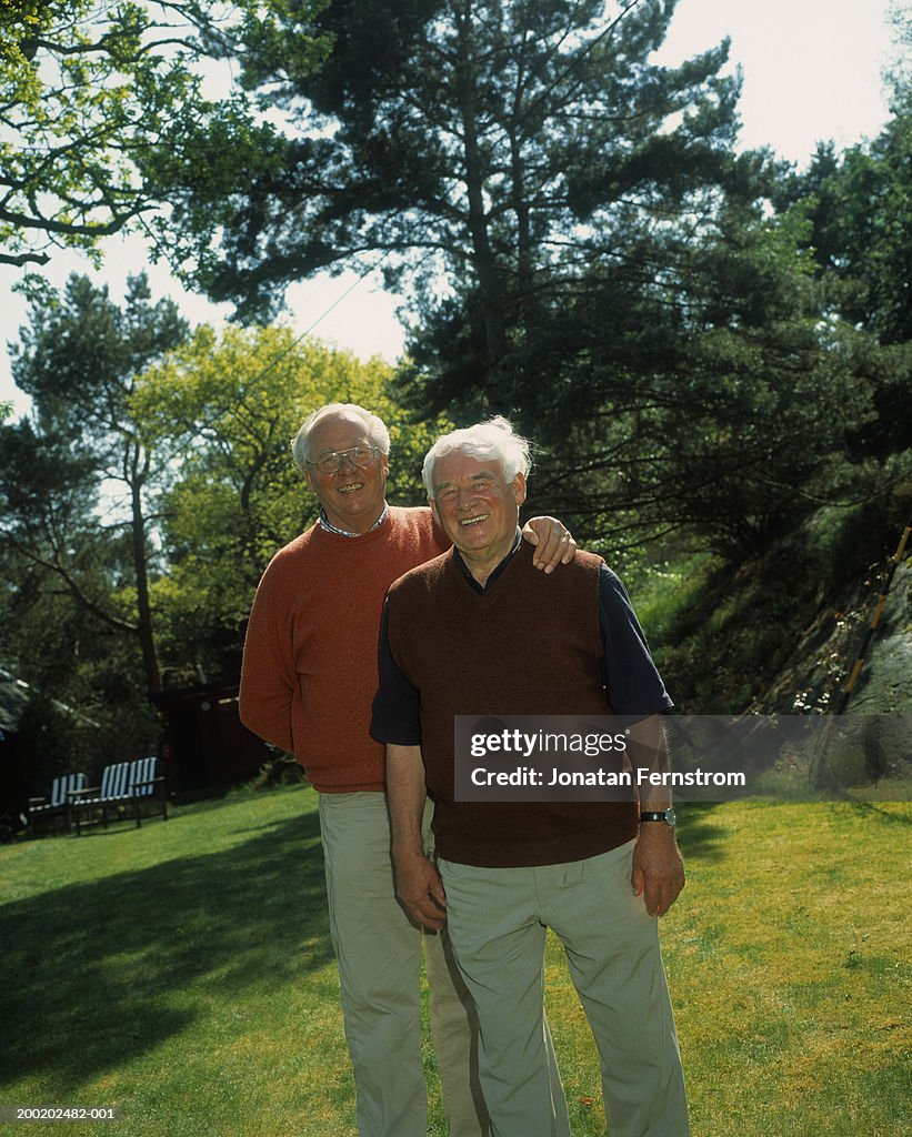 Two senior men standing in backyard, smiling, portrait