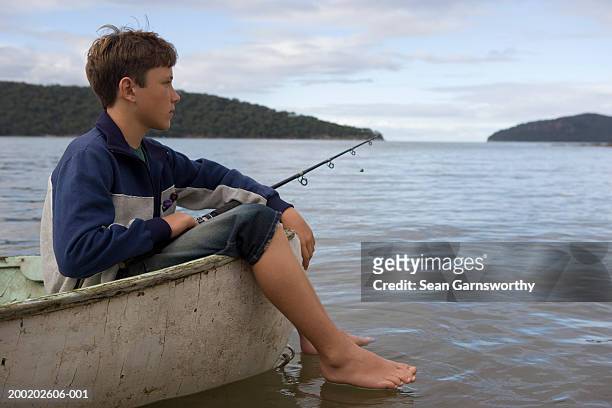 boy (12-14) fishing from boat, feet hanging over side - fishing australia stock pictures, royalty-free photos & images