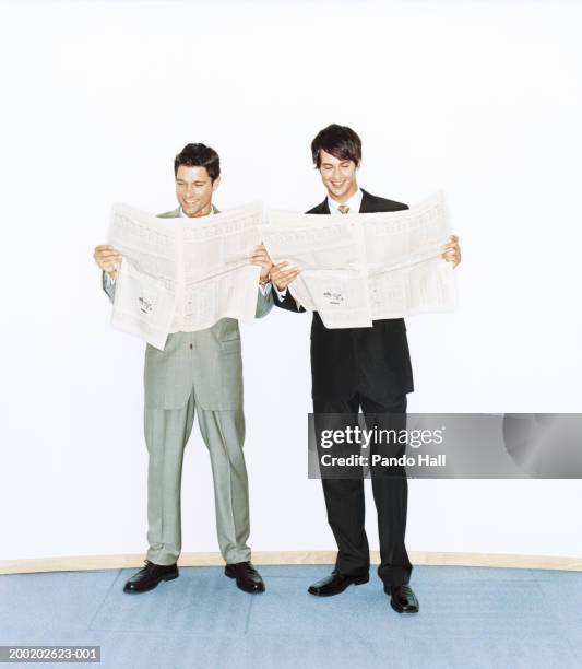 two businessmen reading newspapers, smiling - zeitung lesen zwei personen stock-fotos und bilder