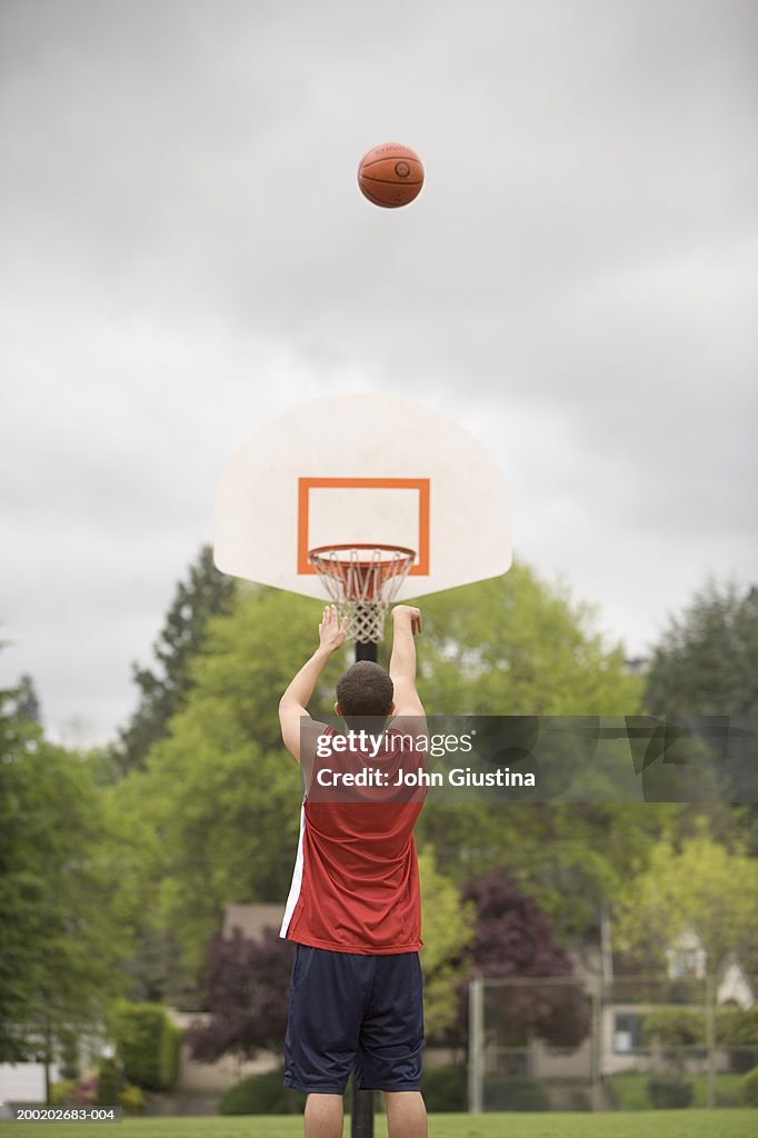 Young man shooting free throw, rear view