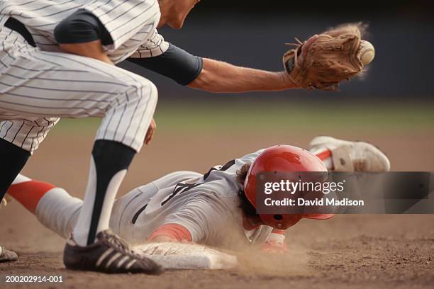 base runner sliding into base, fielder catching ball in baseball game - baseball helmet photos et images de collection