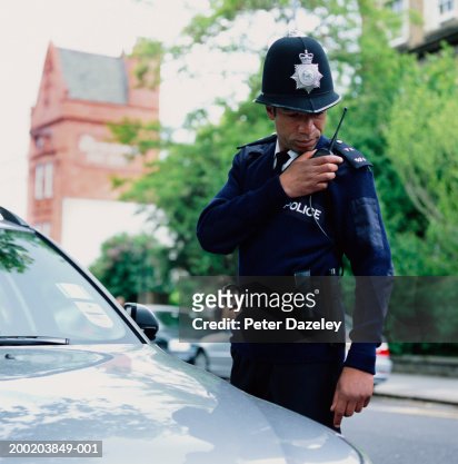 Policeman standing by car using radio