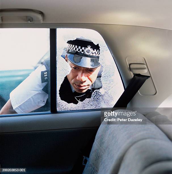 policeman looking through broken window into back of car - police scrutiny stock pictures, royalty-free photos & images