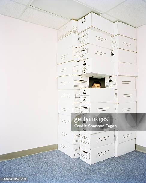 man peeping from stack boxes in empty room - hide and seek stock pictures, royalty-free photos & images