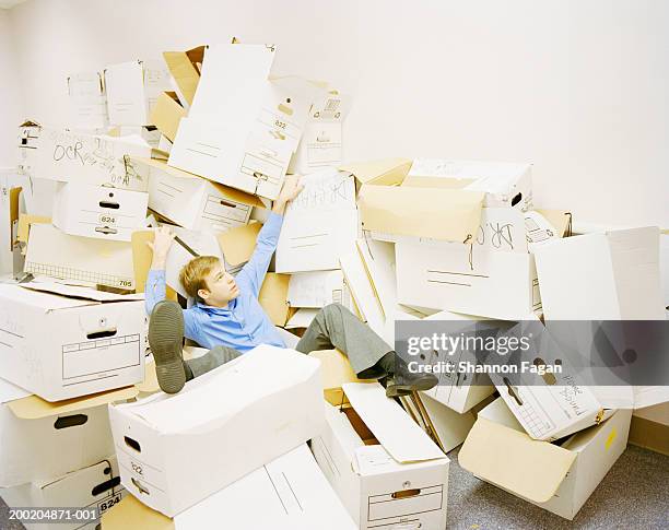 young man sitting between boxes - chaos büro stock pictures, royalty-free photos & images