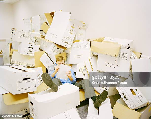 young man with pen and pad between boxes - chaos büro stock pictures, royalty-free photos & images