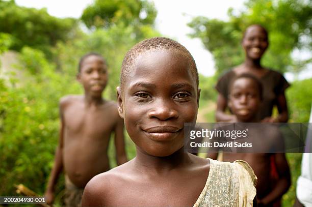 four children (8-18) outdoors (focus on girl smiling in foreground) - uganda stock pictures, royalty-free photos & images