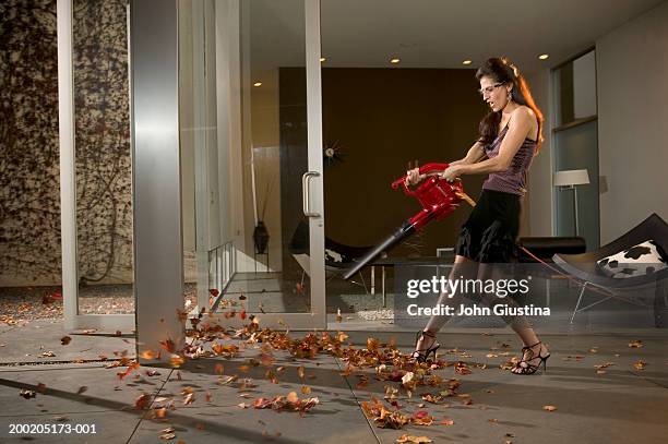 woman using leaf blower to clean living room, side view - leaf blower stock pictures, royalty-free photos & images