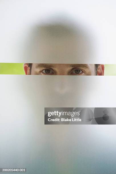 man looking through frosted glass window, portrait (upper section) - verre dépoli photos et images de collection
