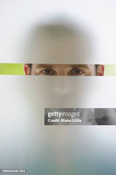 man looking through frosted glass window, portrait (upper section) - frosted glass stock pictures, royalty-free photos & images