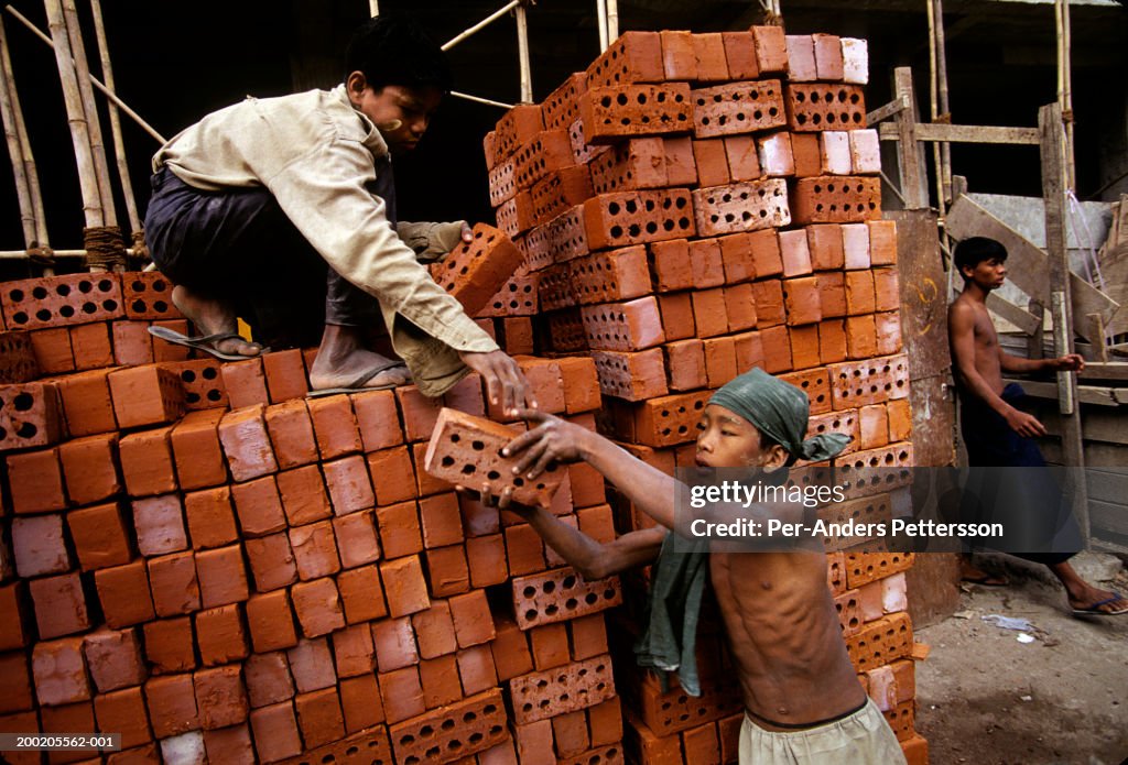 Children carry bricks at a construction site in Rangon, Burma