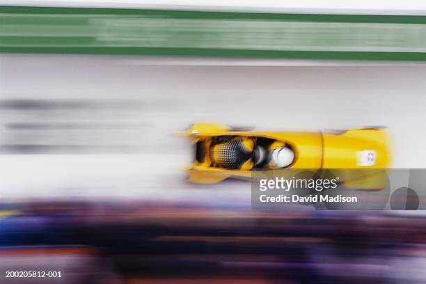 two-man bobsled racing down track (blurred motion) - stroomlijnen stockfoto's en -beelden