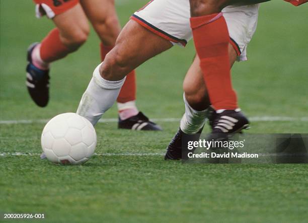 three male soccer players with ball, low section - football player tackle stock pictures, royalty-free photos & images