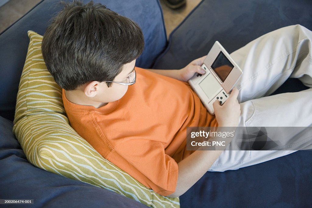 Boy (9-11) playing handheld video game, elevated view