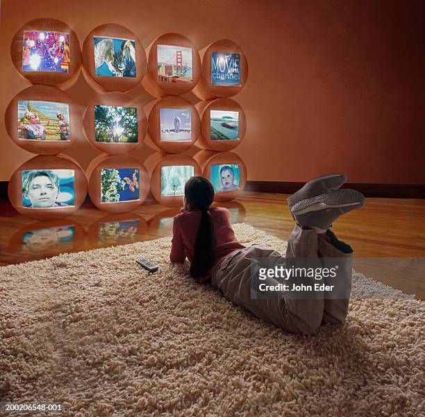 girl (10-12) lying on floor, watching different tv screens - parte di una serie foto e immagini stock