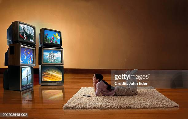 girl (10-12) lying on floor, watching tv screens - multiple screens stockfoto's en -beelden