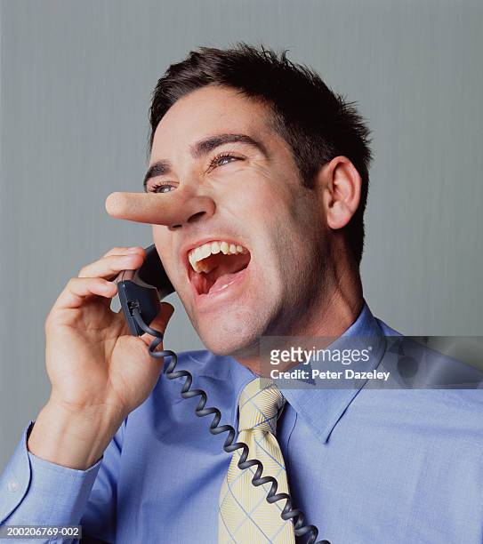 young man on telephone, laughing, close-up - unehrlichkeit stock-fotos und bilder
