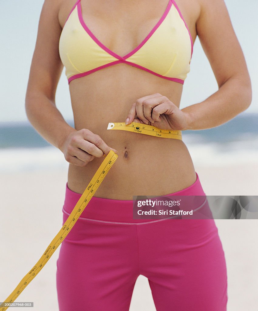 Mulheres jovens em exercício conjunto medir a cintura com Fita Métrica