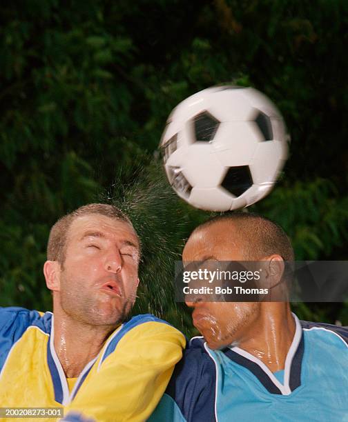 two football players headbutting ball, close-up - header stockfoto's en -beelden
