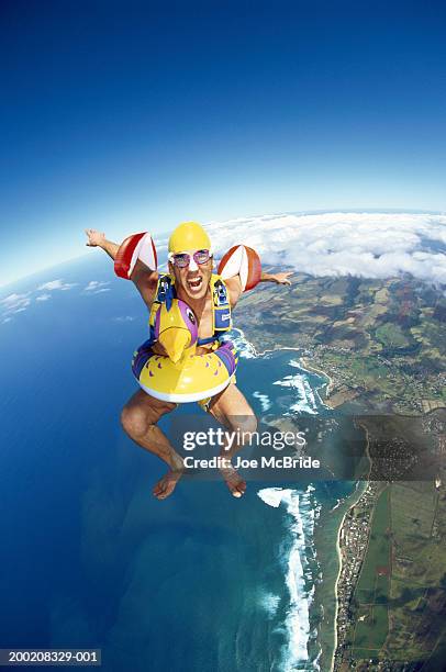 male skydiver wearing water wings and inflatable ring, aerial view - brazaletes acuáticos fotografías e imágenes de stock