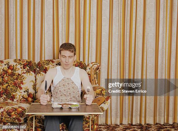 man holding silverware, sitting at serving tray with tv dinner - tv dinner stock pictures, royalty-free photos & images