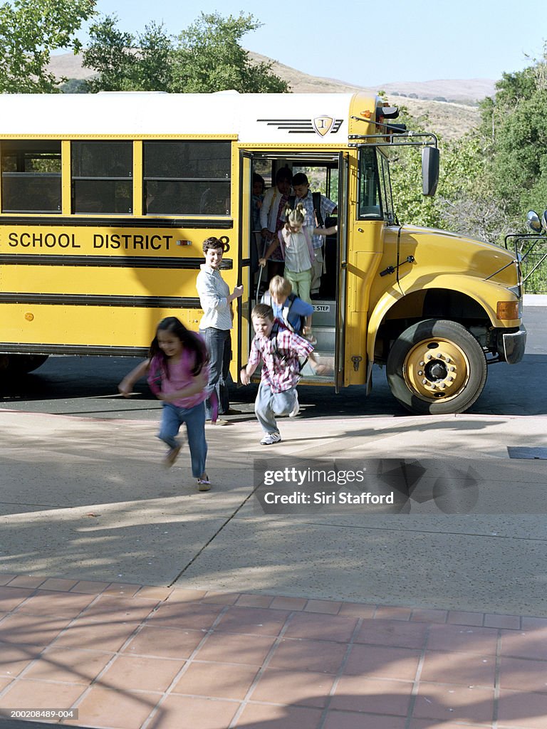 Students (5-7) running off school bus (blurred motion)