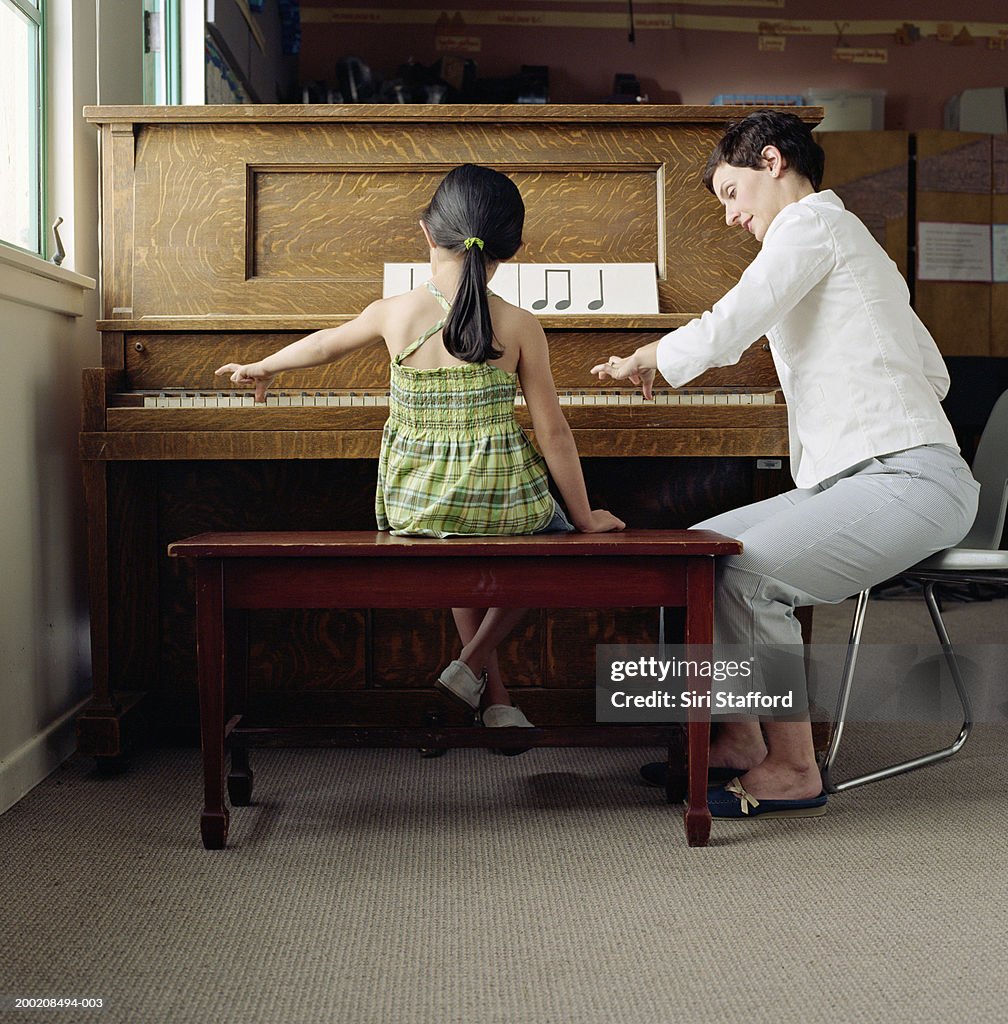 Piano teacher working with student (4-6) at piano