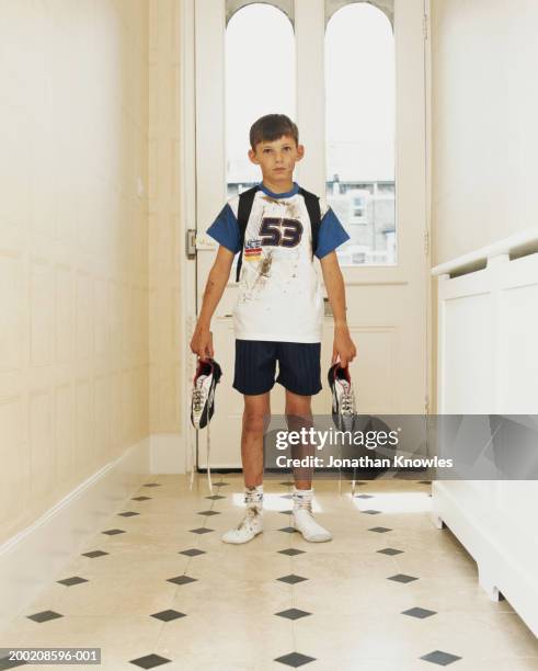 boy (8-10) standing in hallway, holding football boots, portrait - dirty sock stock pictures, royalty-free photos & images