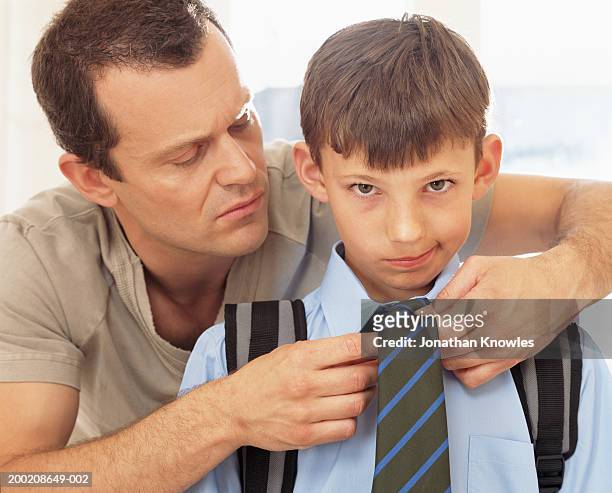 father tying son's (8-10) tie, portrait of boy, close-up - embarrased dad stockfoto's en -beelden