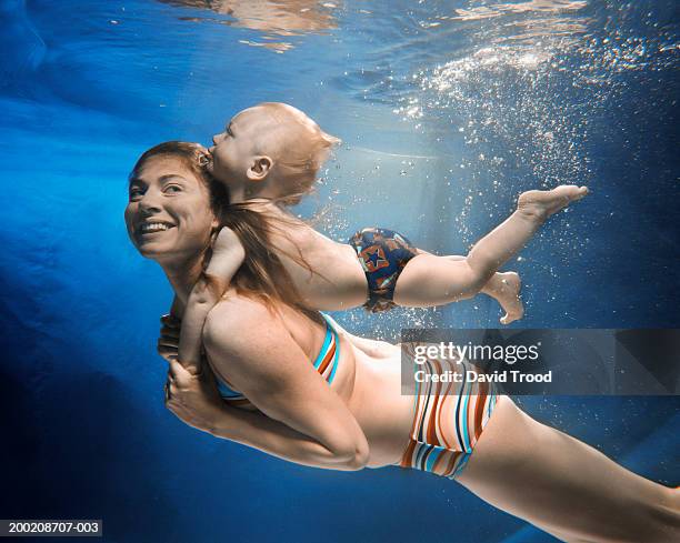 mother swimming with baby boy(12-15 months) on back, underwater view - exercise swim stock-fotos und bilder