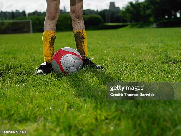 girl (10-12) standing beside soccer ball on field, low section - shin guard stock-fotos und bilder