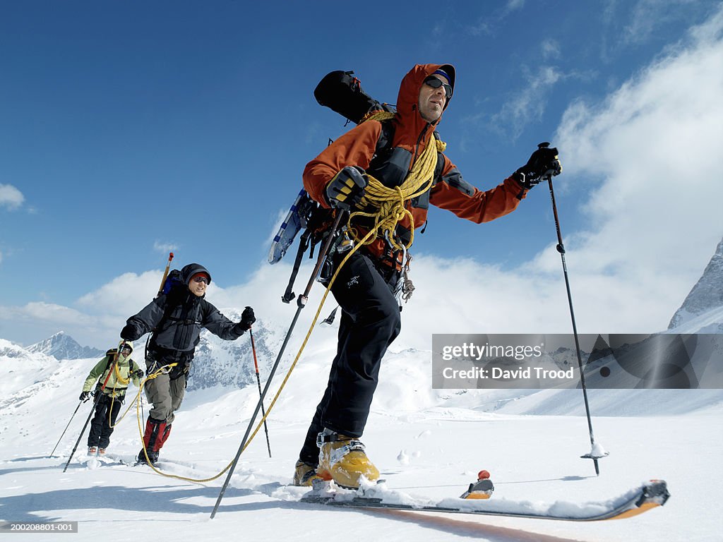 Three hikers in row on snow, low angle view