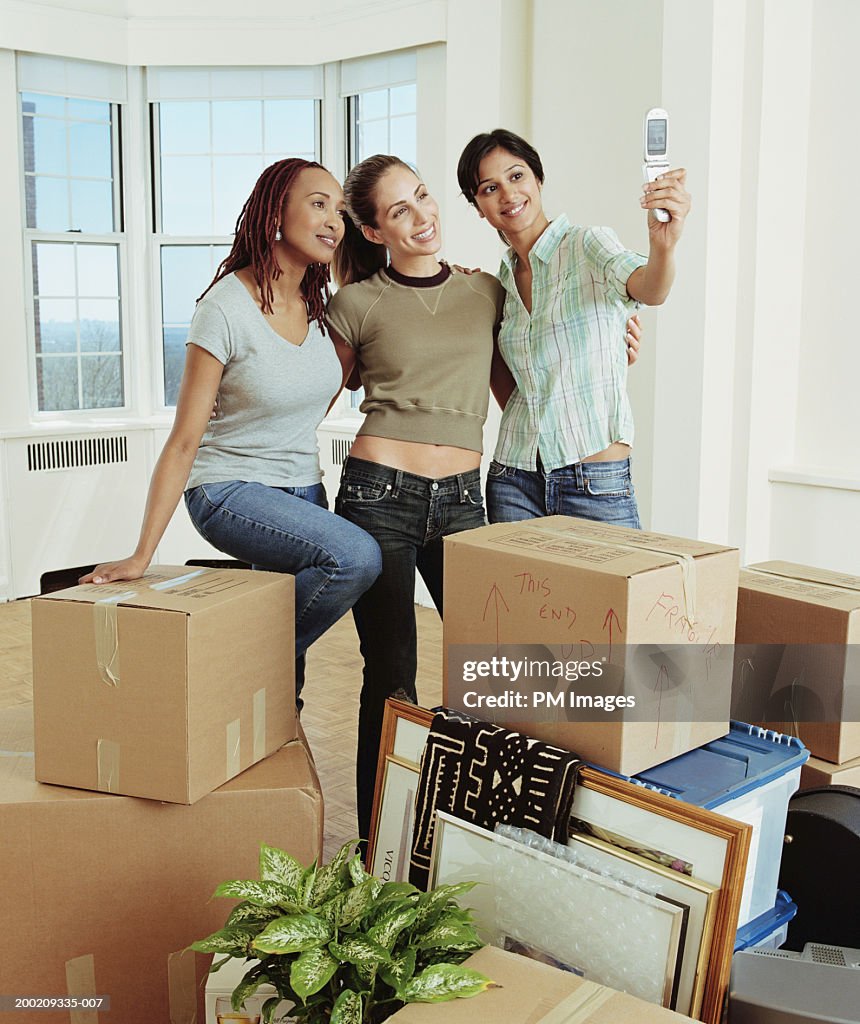 Three young women taking picture with camera phone