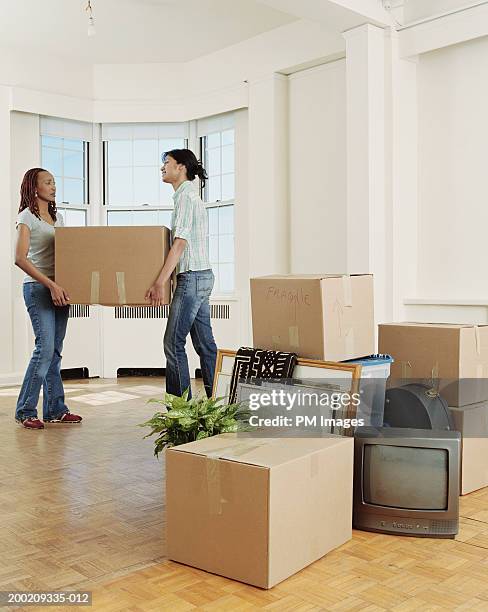 two young women carrying box into apartment - carrying tv stock pictures, royalty-free photos & images